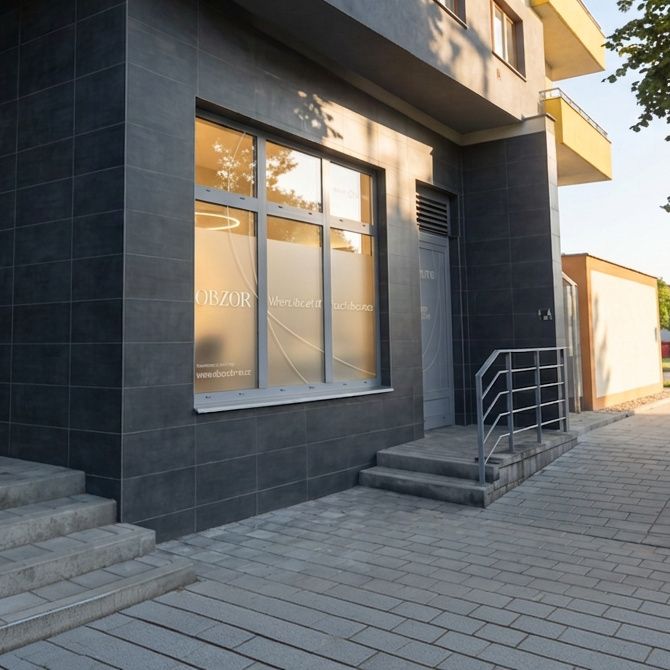 Vstup do ateliéru OBZOR z ulice, prosklená výloha s logem a schody se zábradlím