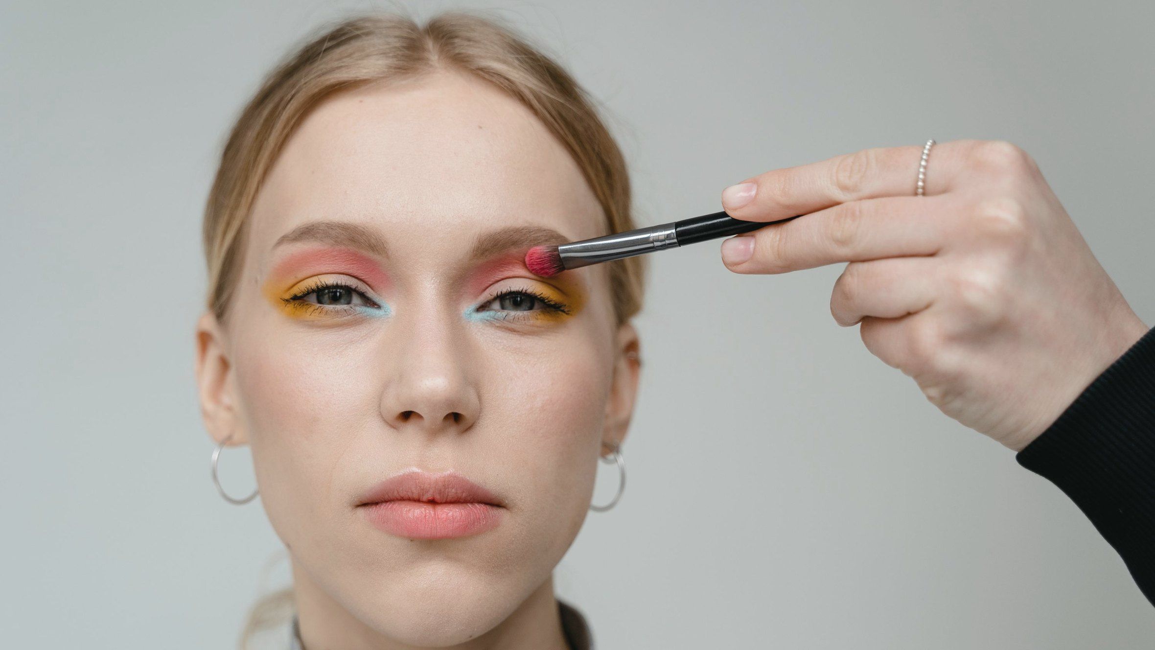 Vizážistka nanáší oční stíny modelce
